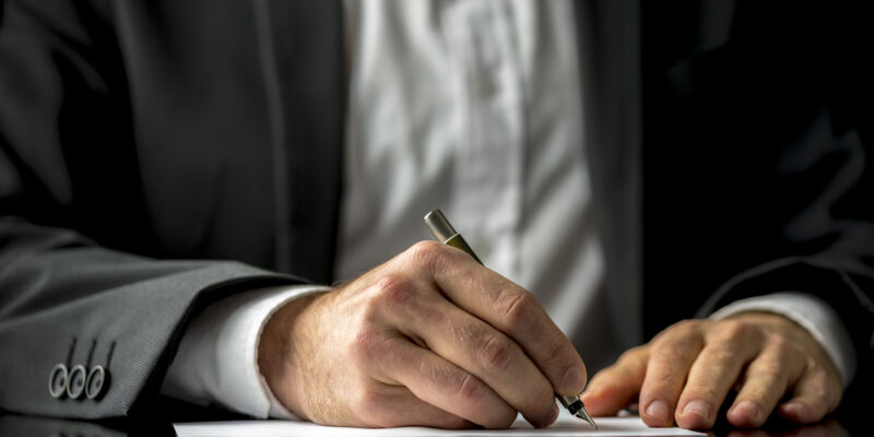 Conceptual image of a man signing a last will and testament document.