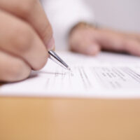 Close up image of businessman signing contract or student having exam test, selective focus